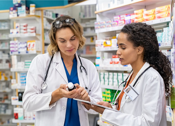 To farmaceuter i et apotek, der kigger på en flaske medicin.